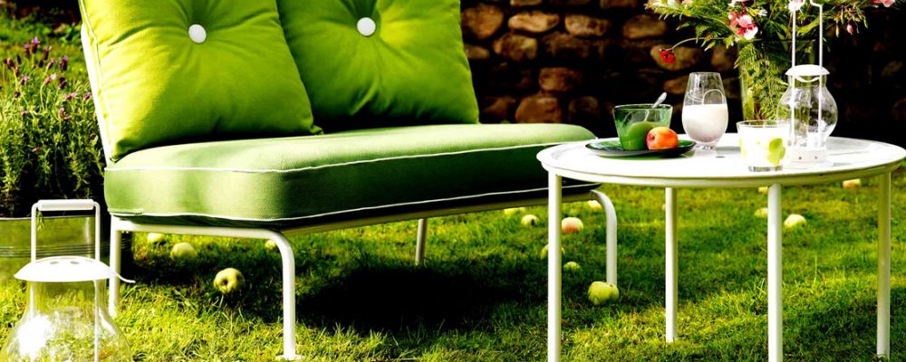 Un pequeño sofá verde en un jardin con decoración chill out de terraza
